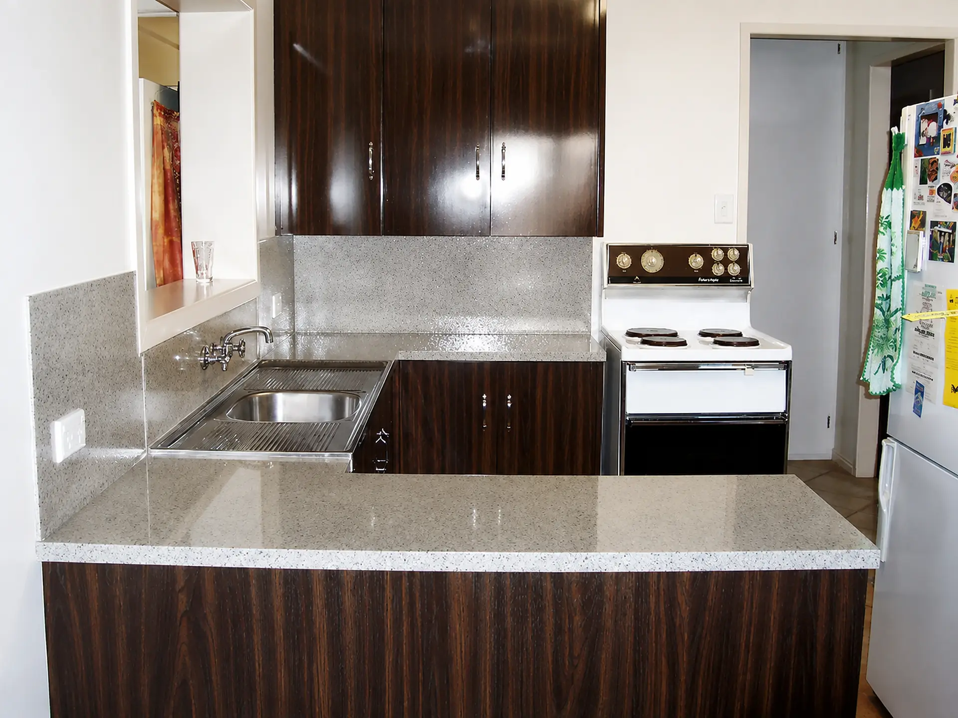 The same kitchen after resurfacing with a light grey speckled benchtop and splashback